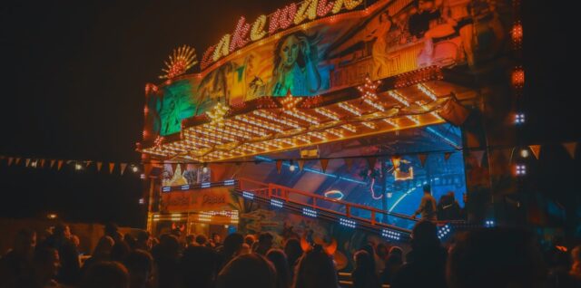 a crowd of people standing around a carnival ride at night